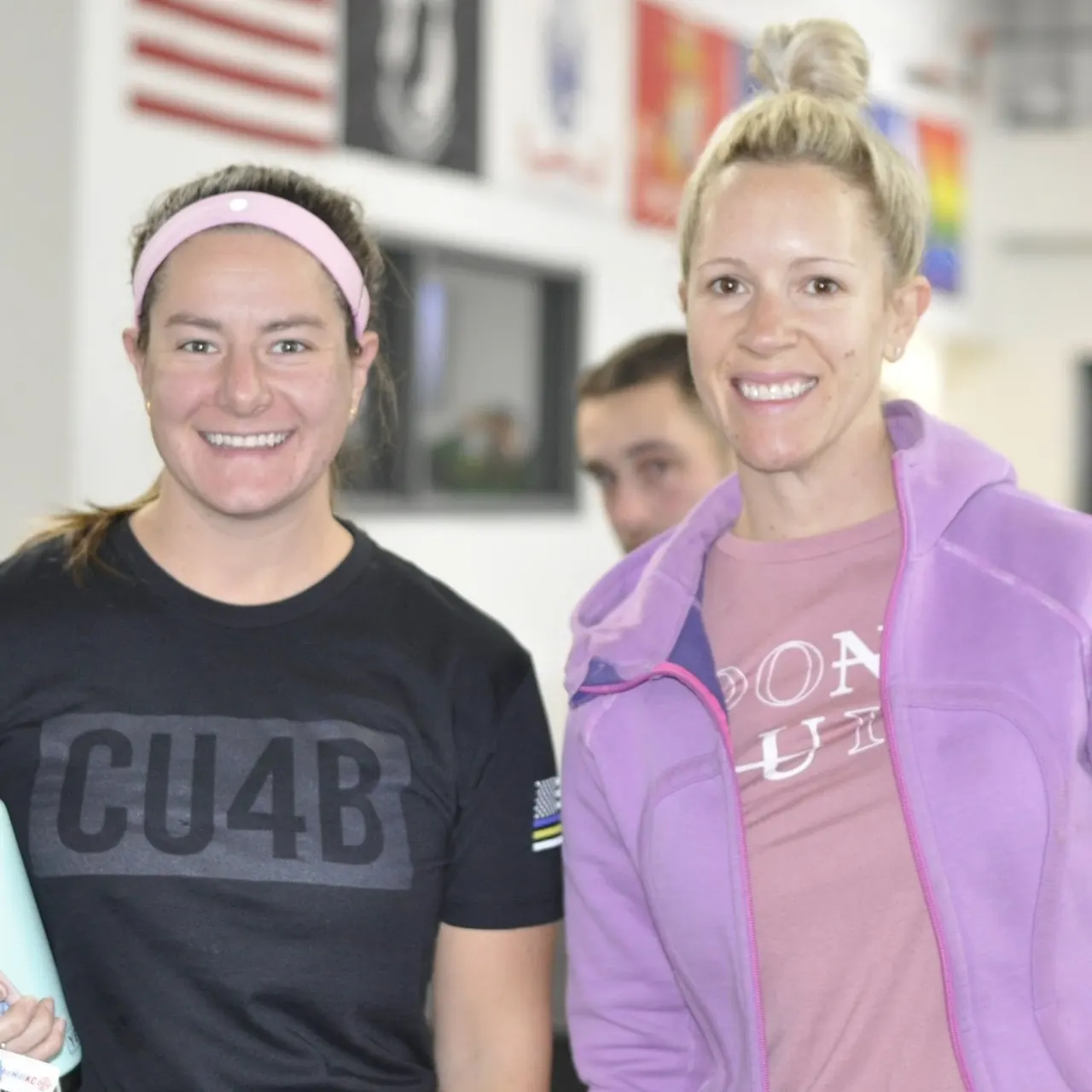 Two women smile together at a Chalk Up for Burpees gym event.