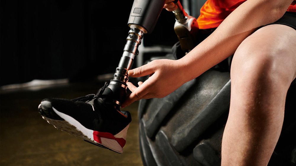 An athlete adjusts a running-blade prosthesis while seated.