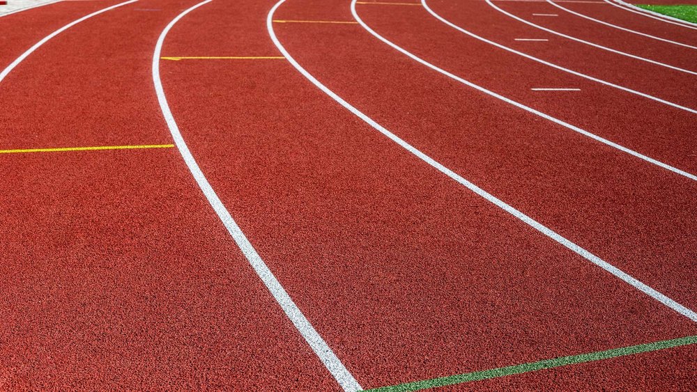 Curved lanes of an empty red running track.