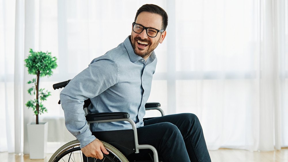 A smiling man in a wheelchair in a bright room.
