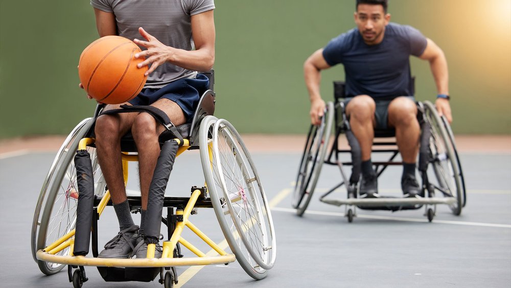 Two wheelchair basketball players on a court, one holding the ball.